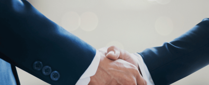 Two professionals shaking hands in an office, symbolizing the successful negotiation of a Broker Agreement.